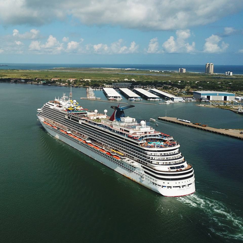 Aerial photo of a large white cruise ships sailing into Galveston, Texas