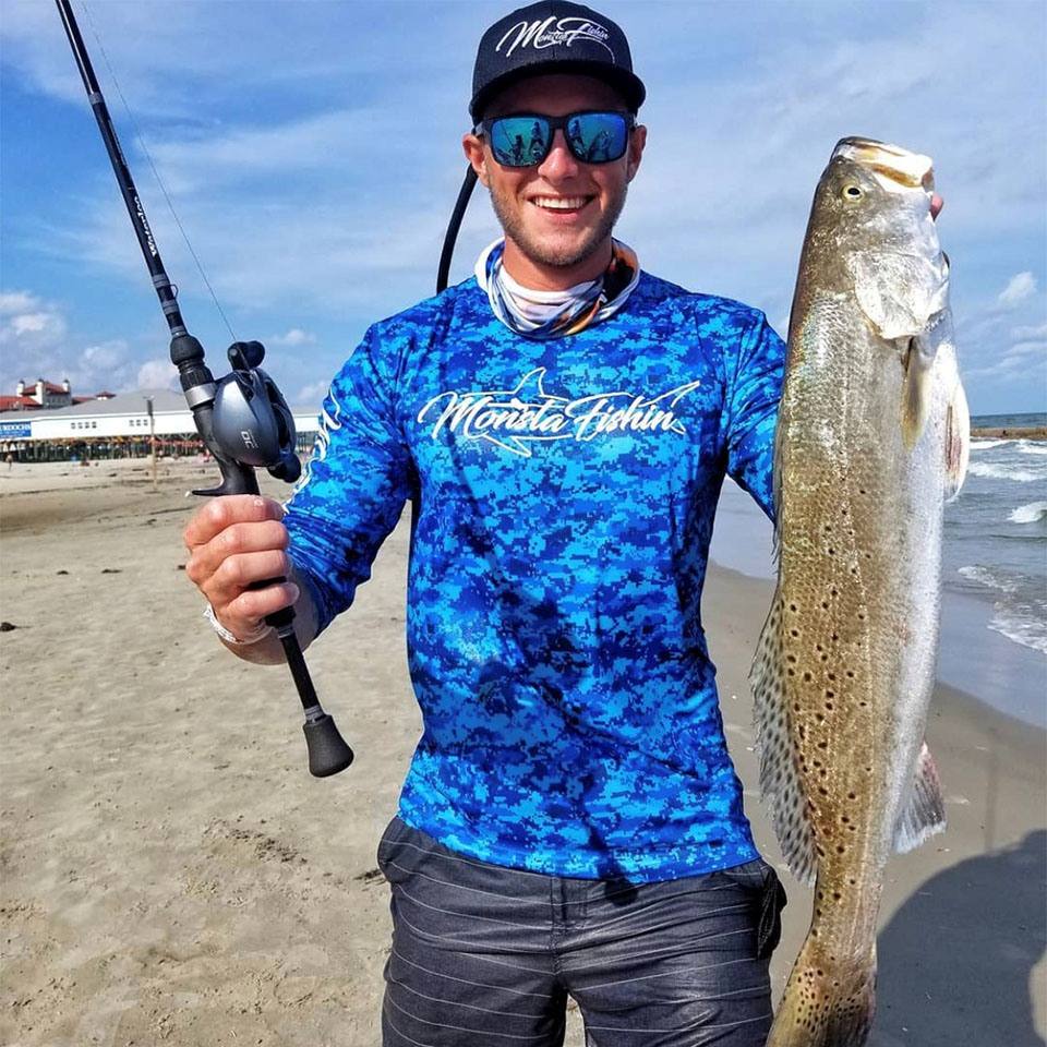 a man holding a speckled trout, caught while fishing in Galveston