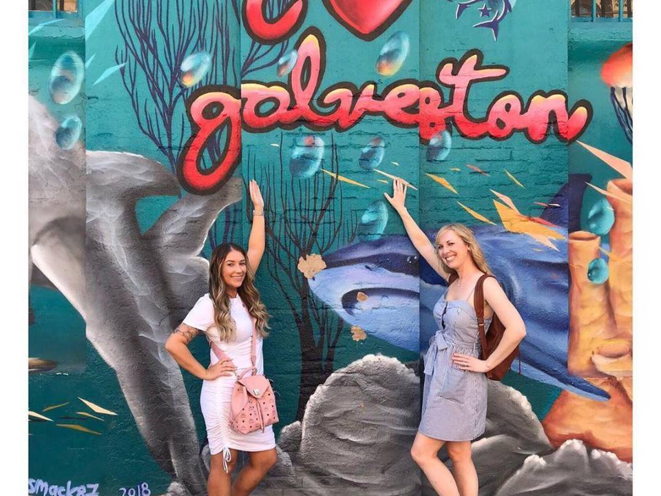 Friends posing in front of the Shark Shack Mural by The Strand.
