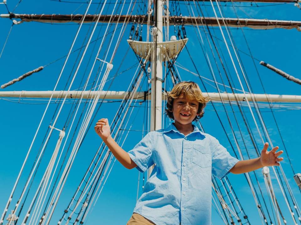 A kid standing in the at the Galveston Historic Seaport and 1877 Tall Ship Elissa.