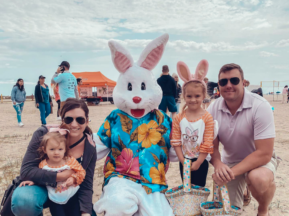 a family of four pose with a white easter bunny wearing an Hawaiian shirt on the beach in Galveston