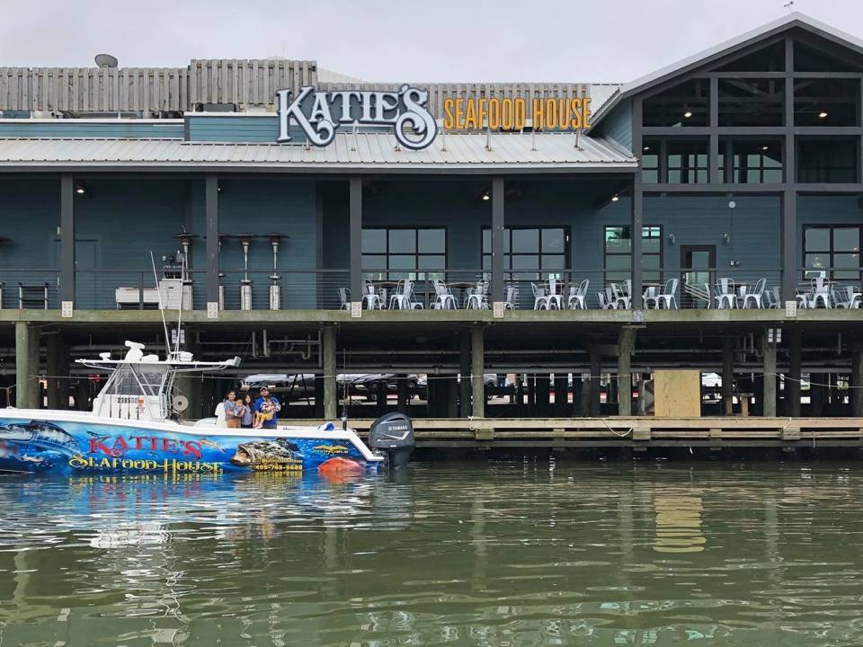 a boat floats in front of the outdoor dining area at Katies Seafood House in Galveston TX