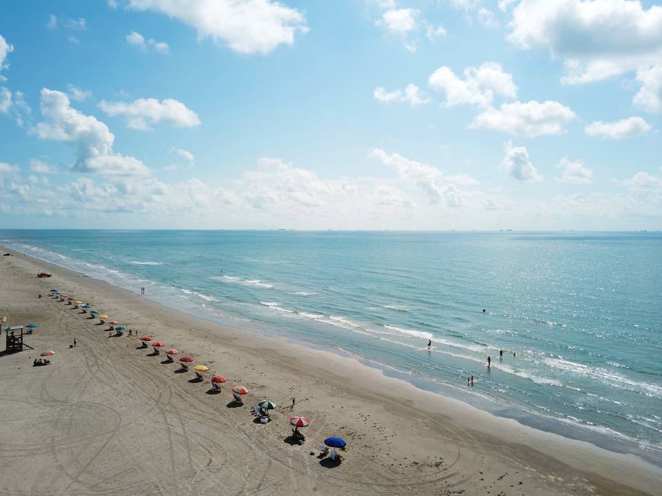 aerial view of a row of beach umbrellas and chairs on Stewart Beach in Galveston, Texas on a bright sunny day