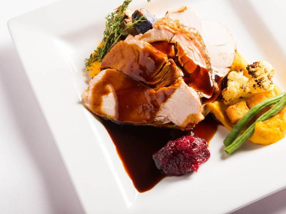 top-down view of a white plate topped with turkey, cranberry sauce, assorted vegetables, and a sauce
